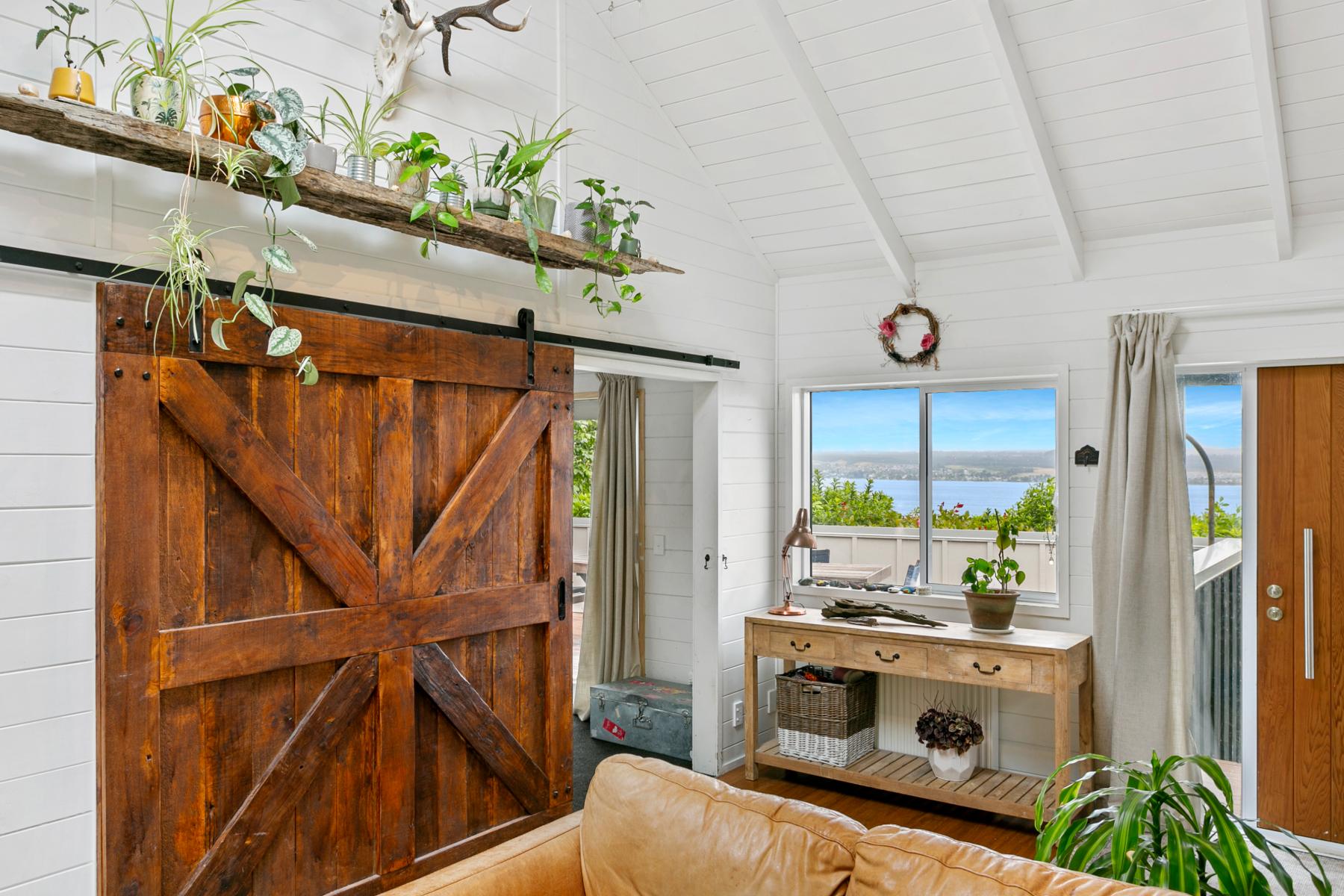 Rustic barn door and lounge with Lake Taupō through the window